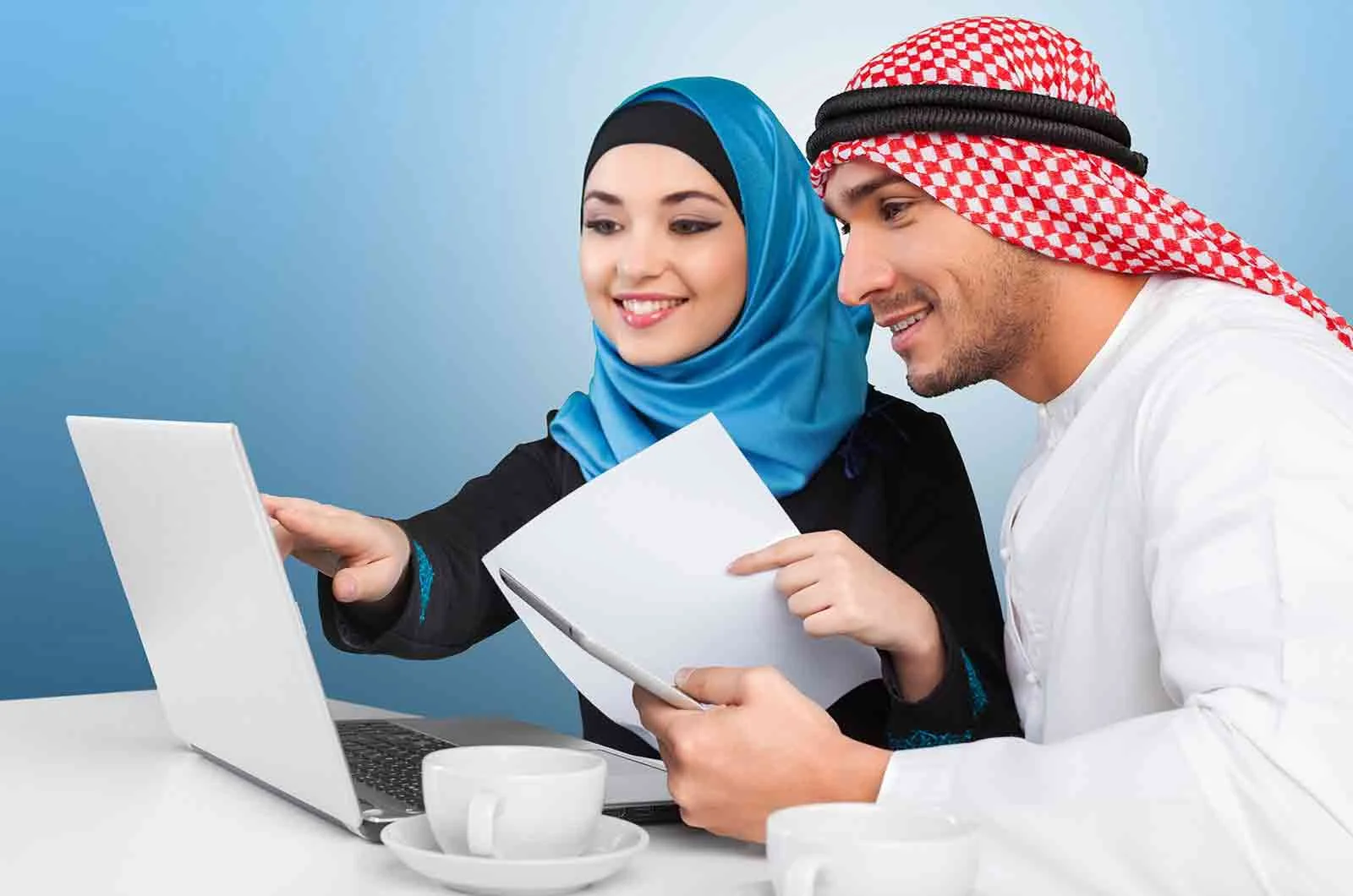 A girl wearing hijab and a guy wearing traditional Arabic clothing, sitting on a desk with a laptop. Concept of English to Arabic translation.