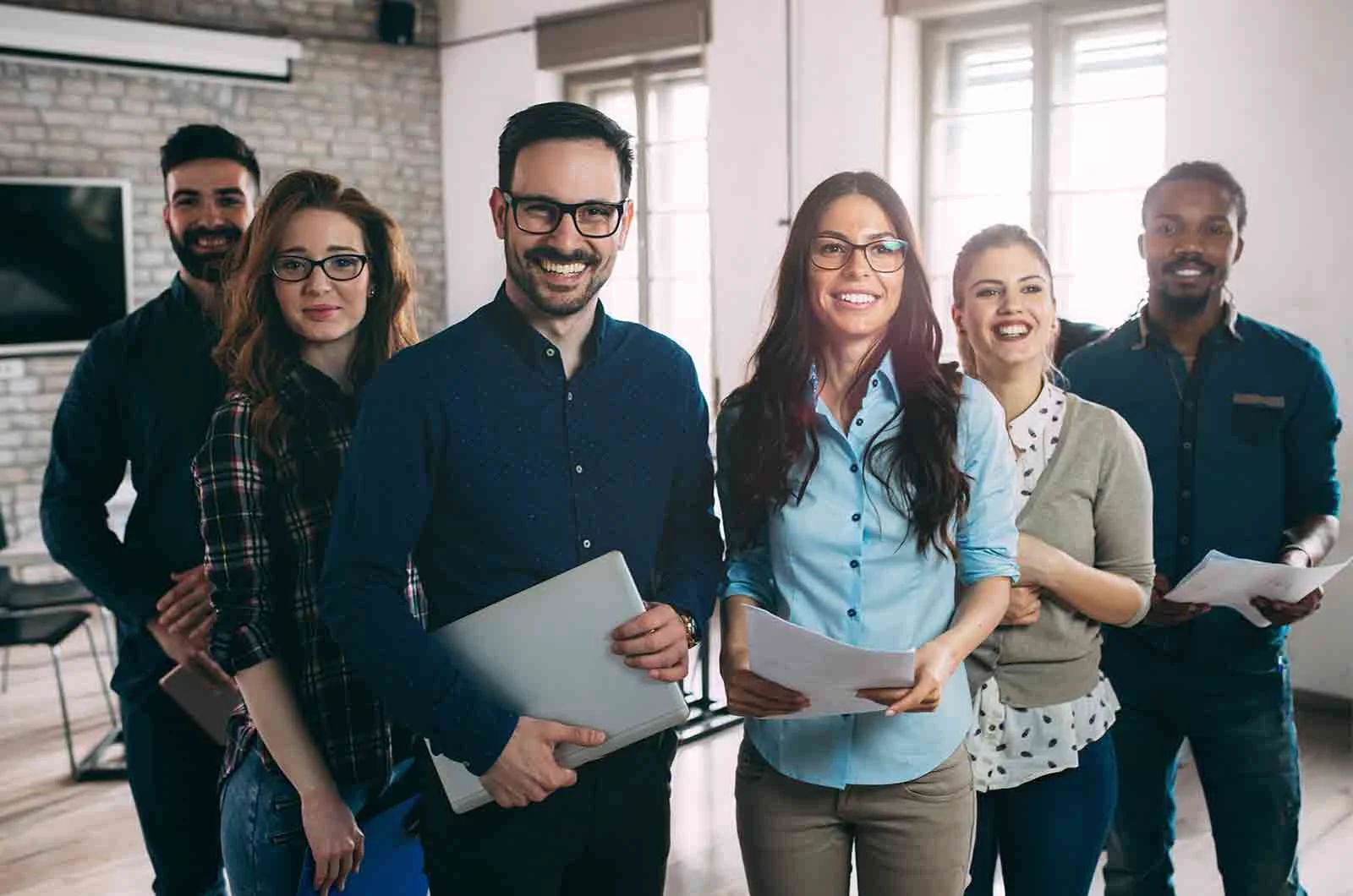 Employees standing next to each other and smiling to take a picture. Concept of translation services UK.