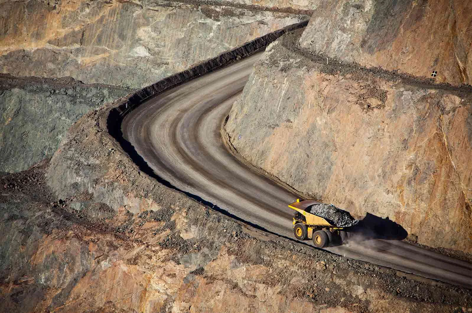 Truck carrying black rocks driving on a mountain road. Concept of professional oil and gas translation services.