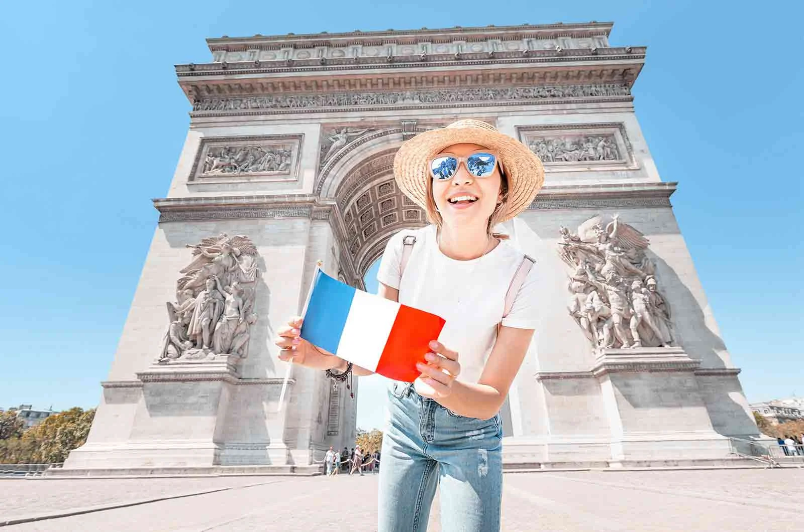 A girl with a French flag, in front of the Arc de Triomphe. Concept of French translation.