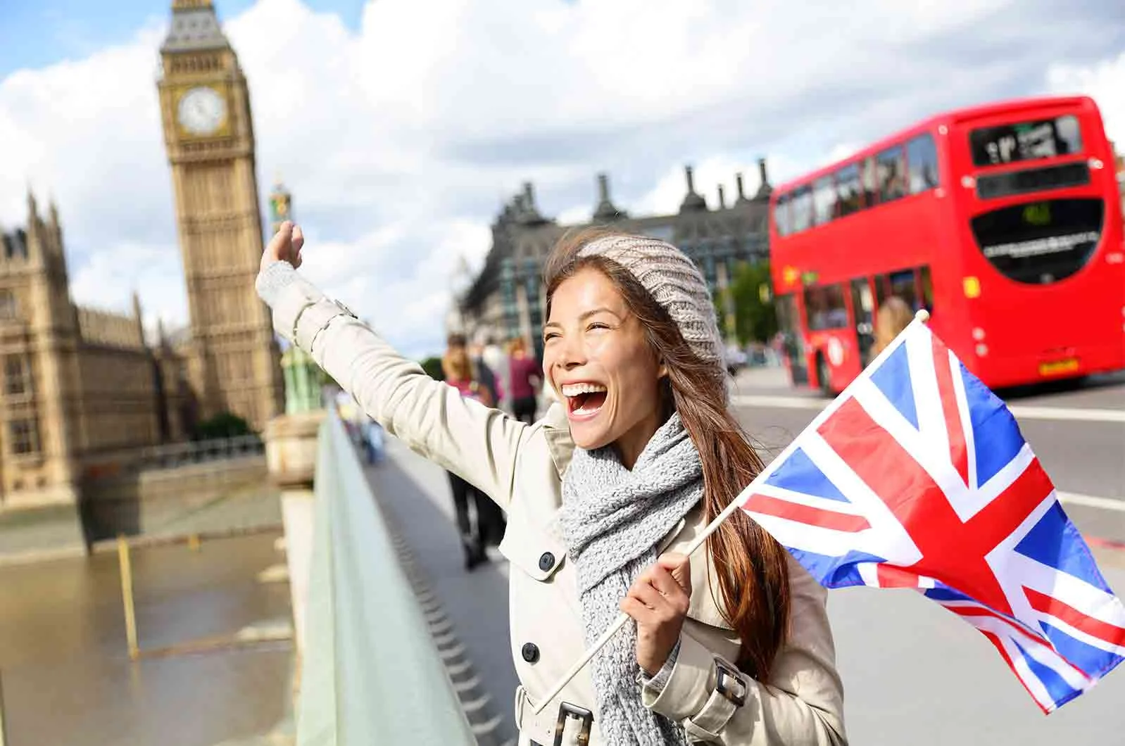 Asian woman standing in front of Big Ben, holding the United Kingdom's flag. Concept of translating languages.