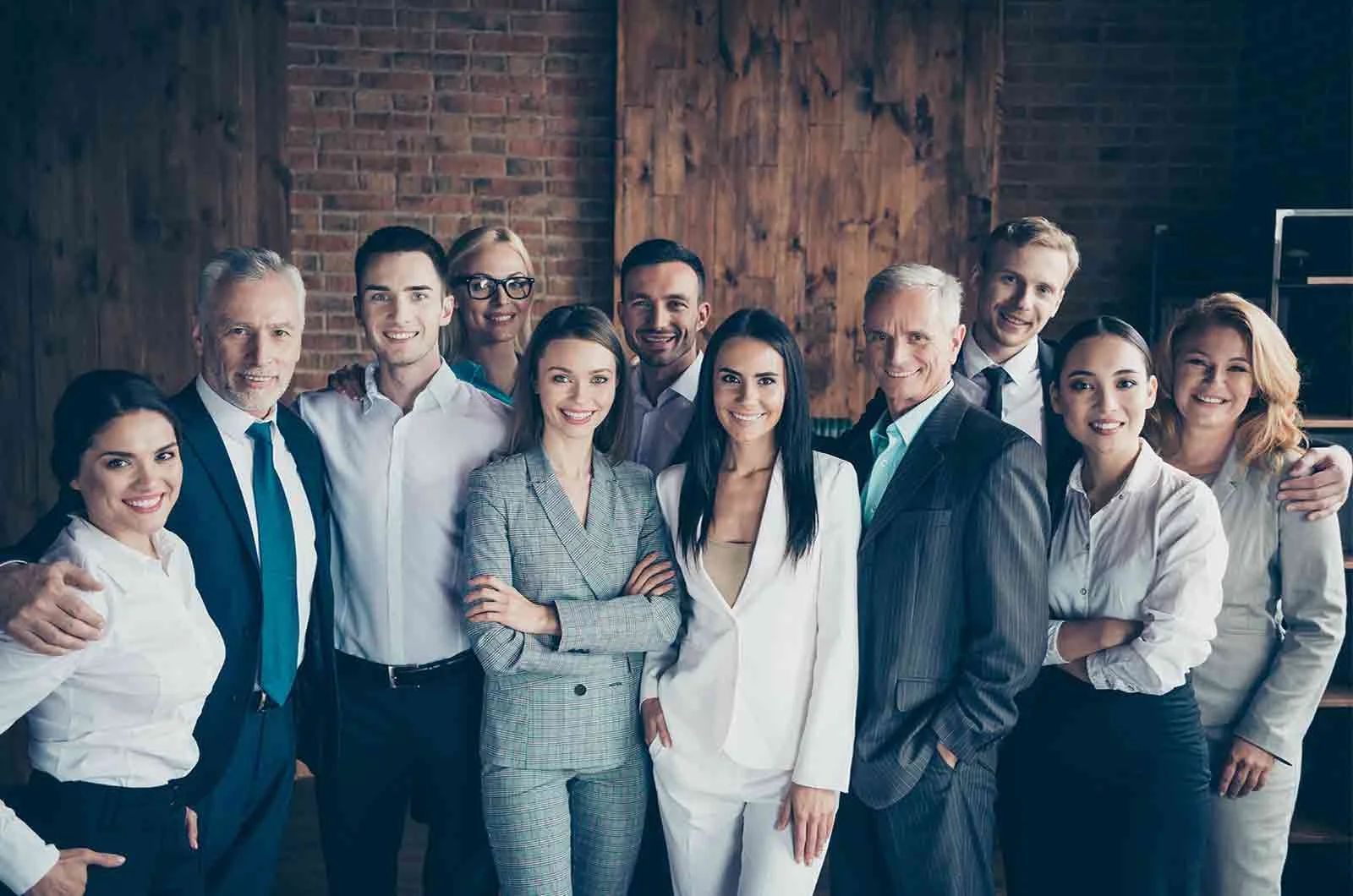 Team members of men and women standing in the office and smiling.