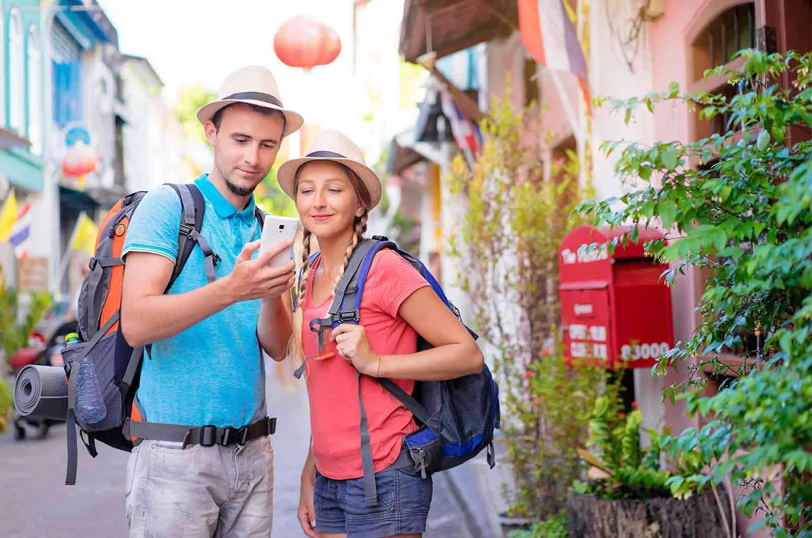 A couple carrying travel and camping backpacks, looking at the phone. Concept of tourists who must know Chinese words for summer festivals.