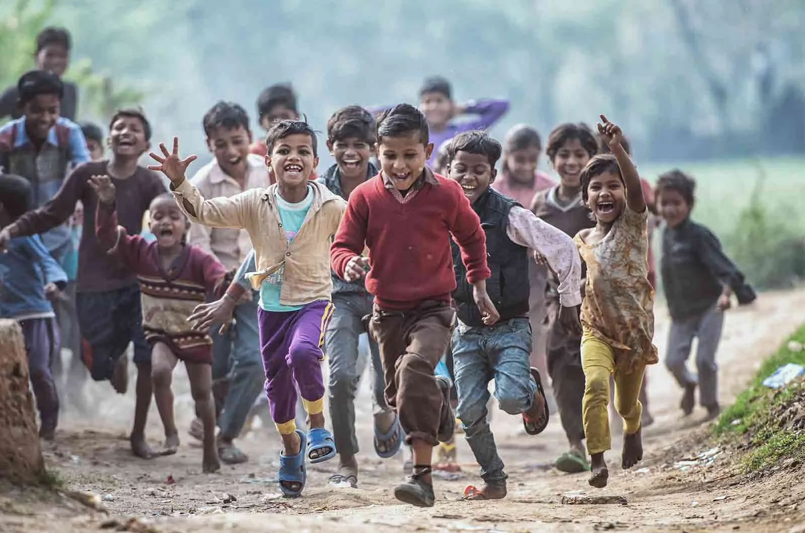 A group of poor children running on a dirt road, barefoot. Concept of charity translation and professional charity translators.