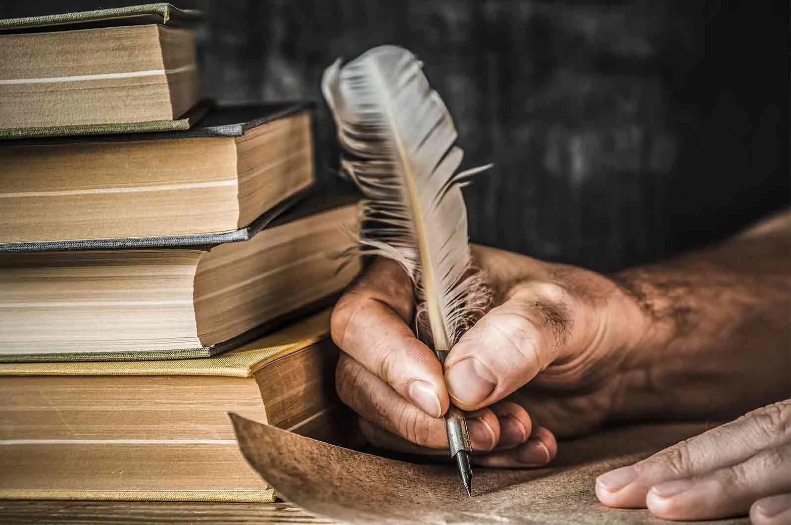 A man writes on old paper with a quill next to books. Concept of English language translators.