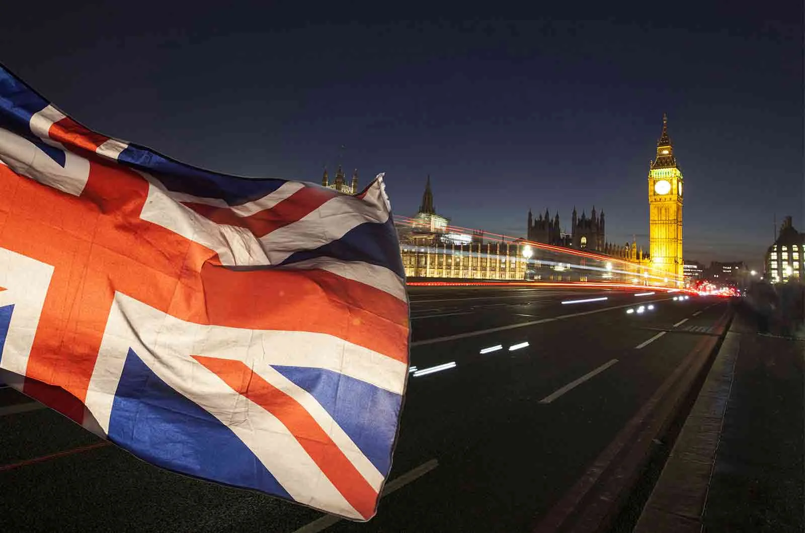 The flag of The United Kingdom and the Big Ben at night flutters in London, Britain. Concept of language services and translation companies.