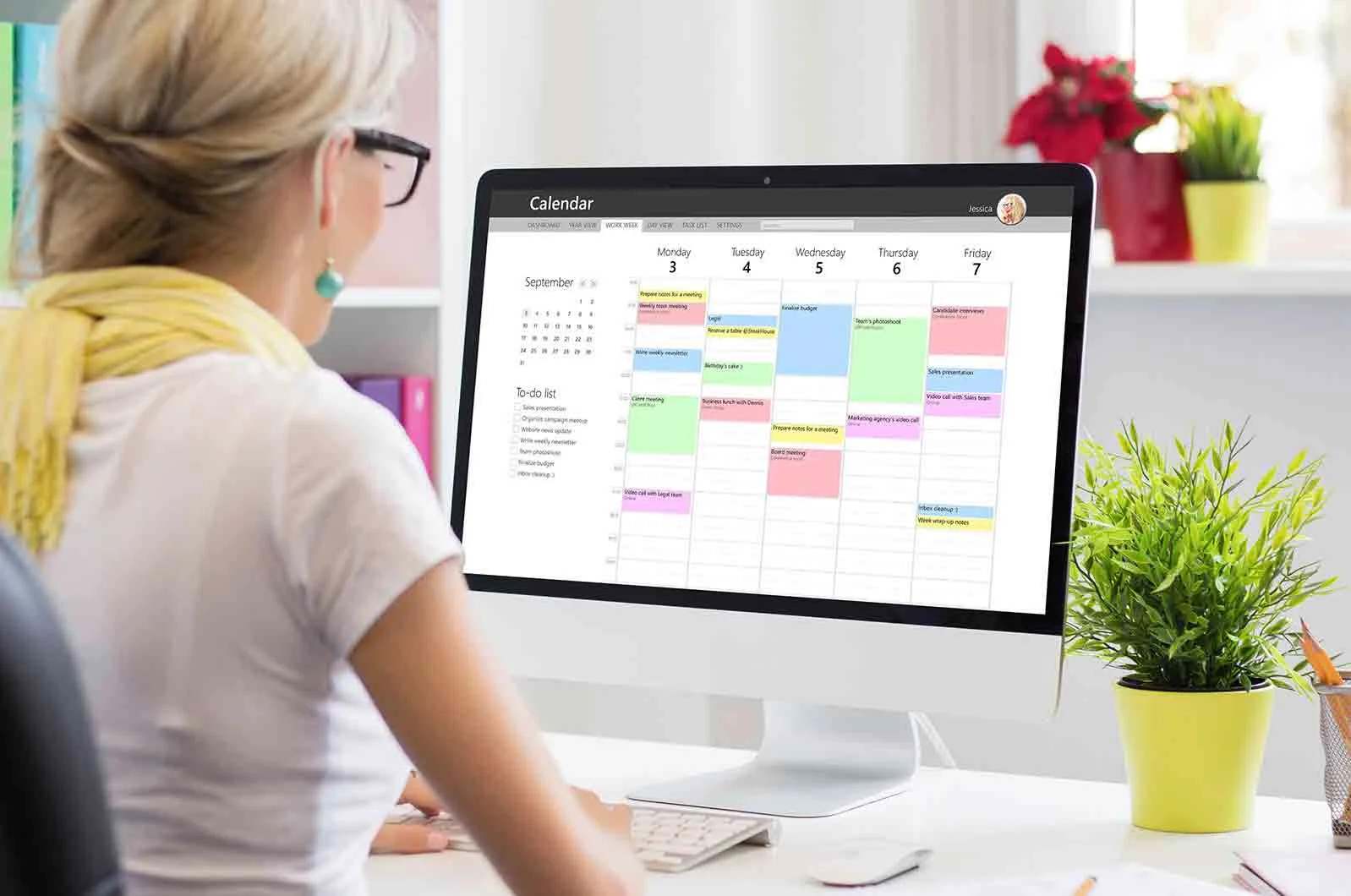Professional woman sitting on desk and using calendar on computer. Concept of time management strategy.