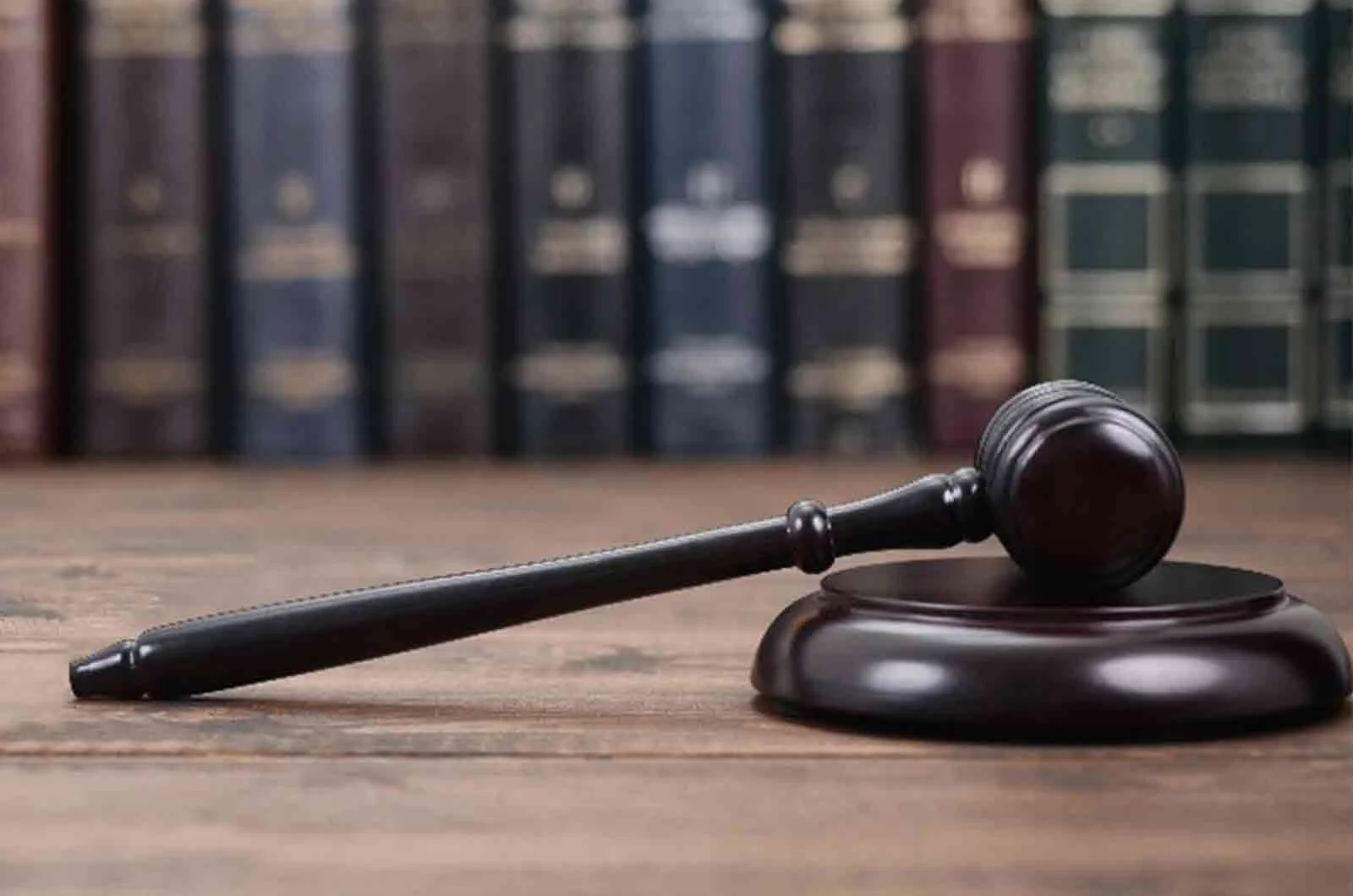 A brown judge's gavel on a desk in a library with books in the background. Concept of certified legal document translation.