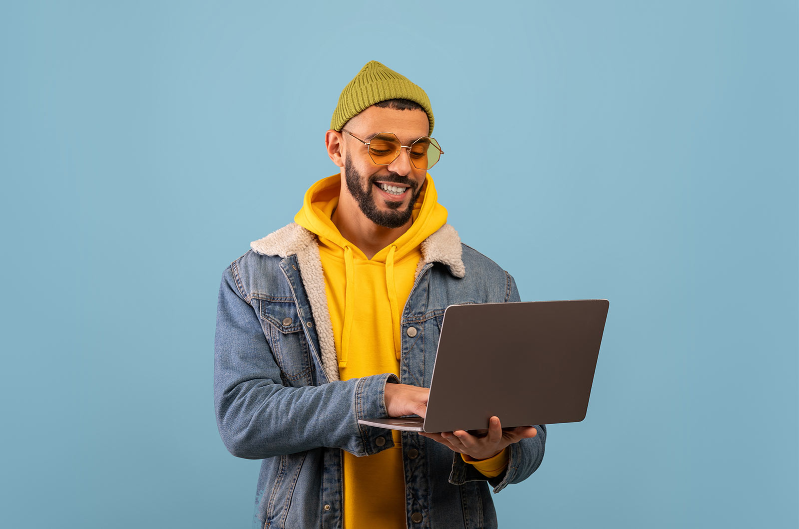 An Arabic man standing with a laptop in his hand and smiling. Concept of eCommerce website translation by professional translators for Arabic.