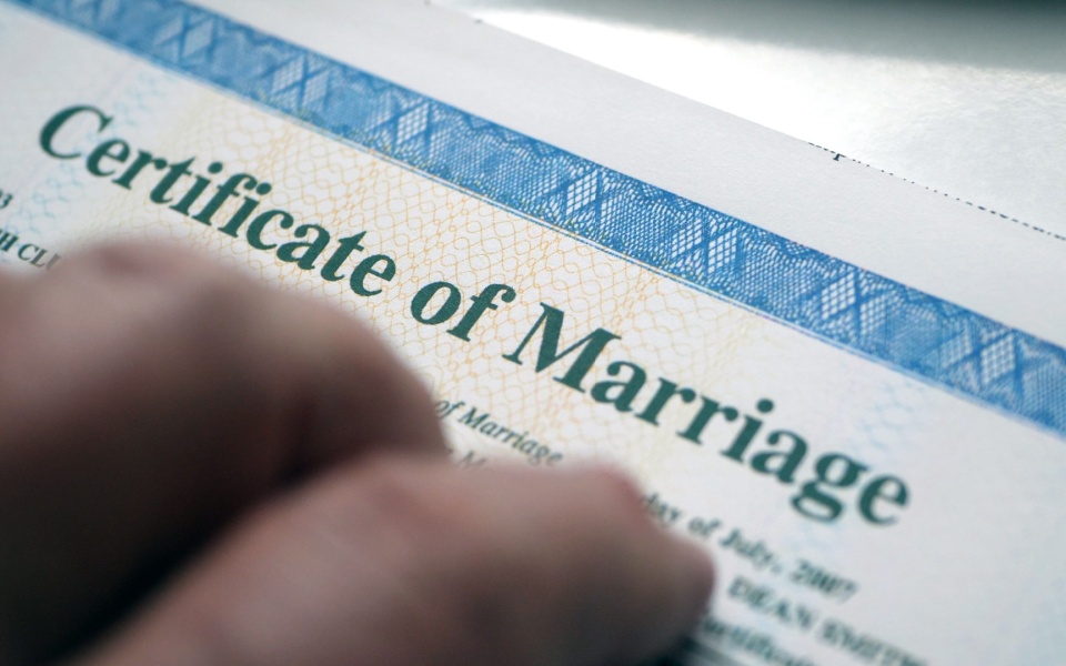 Man hand tapping on a marriage certificate that needs translation.