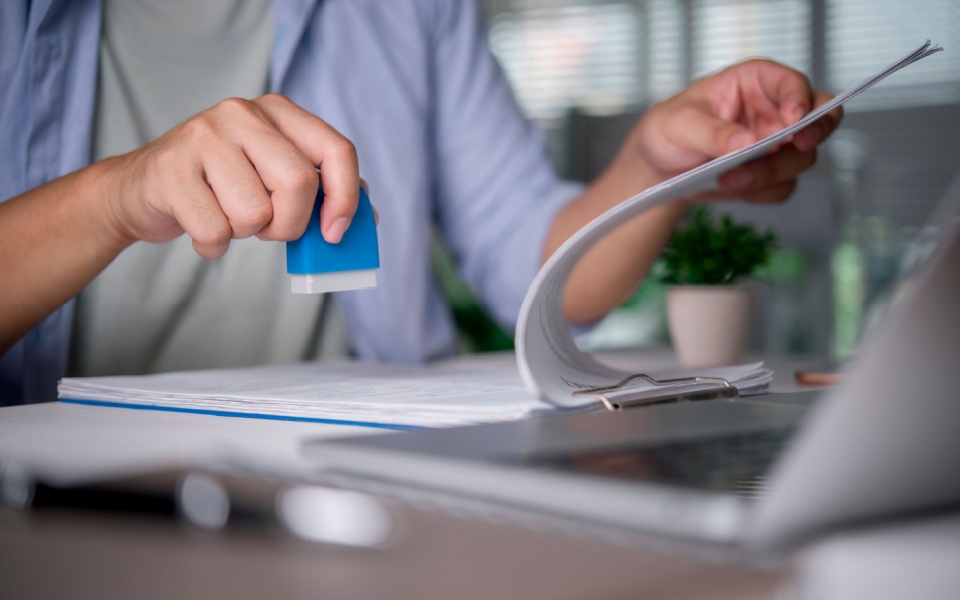 Man working with official document translation and stamping a certificate of translation accuracy in an office. 