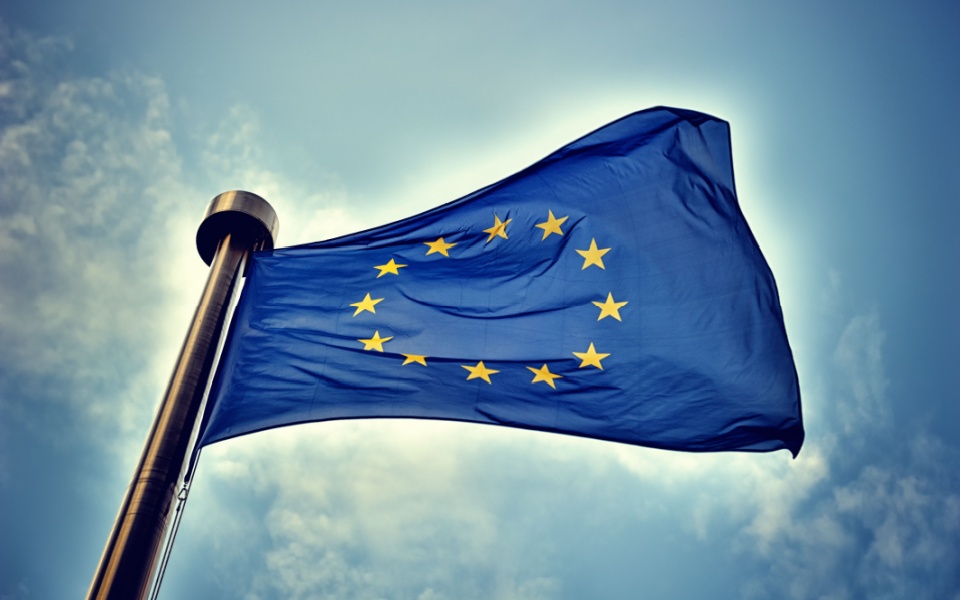 European Union flag on blue sky background.