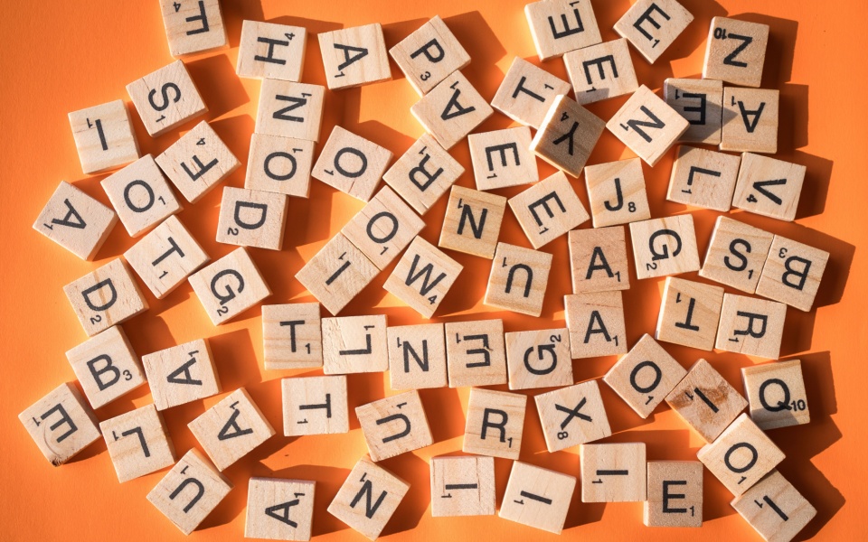 English alphabets appeared as wooden cubes on an orange background. History of the alphabet and historical document translation.
