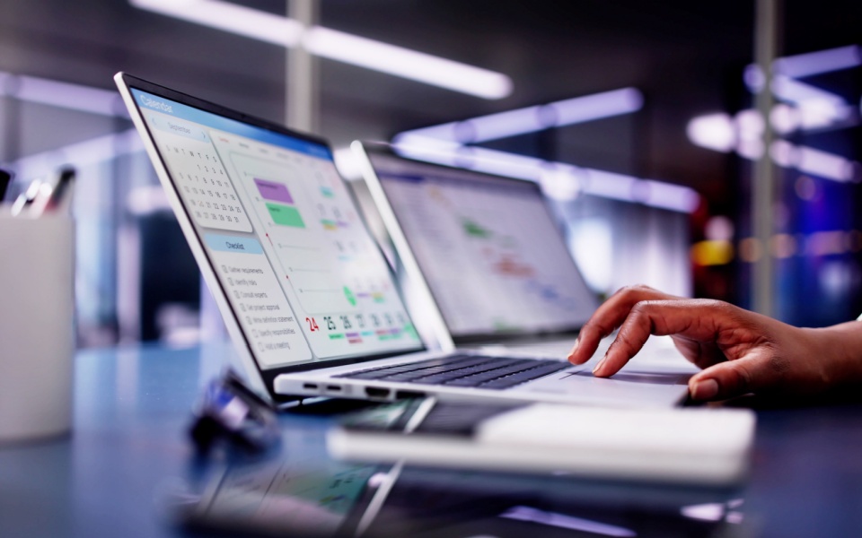 Hands of an employee managing tasks and schedules with translation project management system using laptop in a modern office. 
