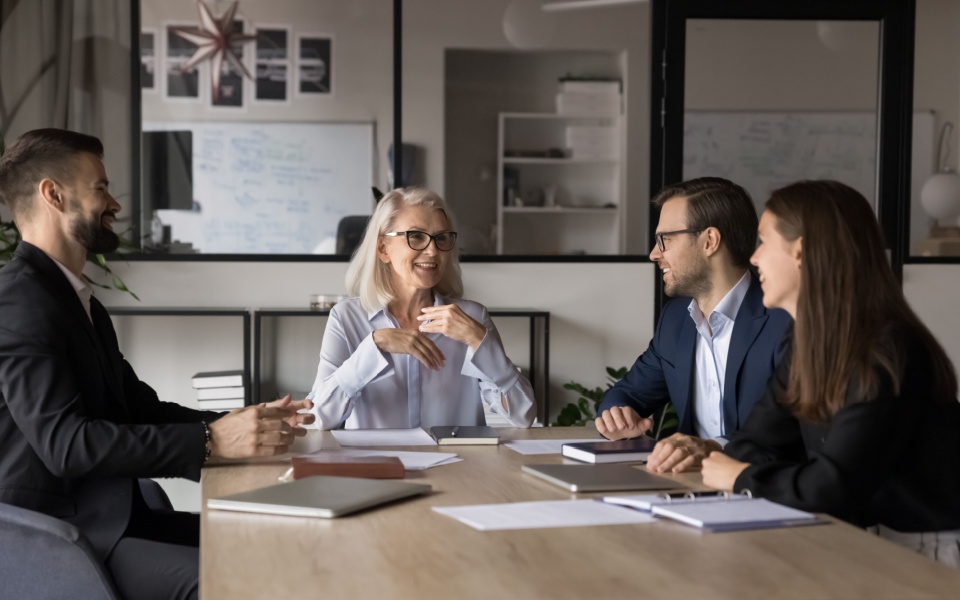 Senior employee explaining corporate goal to other 3 employees using handbooks. An example of employee handbook translation. 