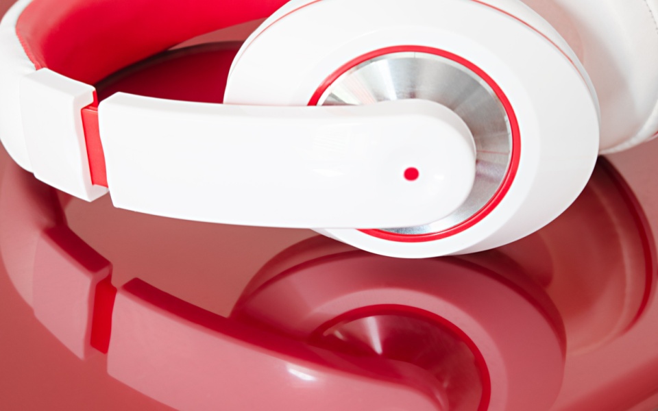 Red and white colorful headphones for language learning with video games and red laptop on the table. 