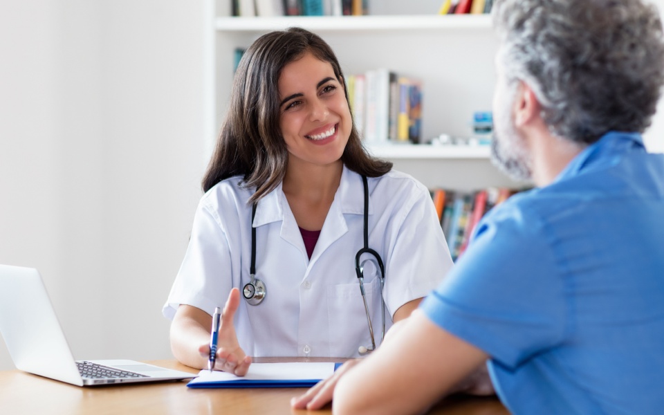 Mexican female doctor talking with patient at hospital. An example of English to Spanish medical translation services.