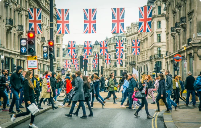 Shoppers in Regent street in London crossing the road with rows of British flags. Concept of UK translation services company. 