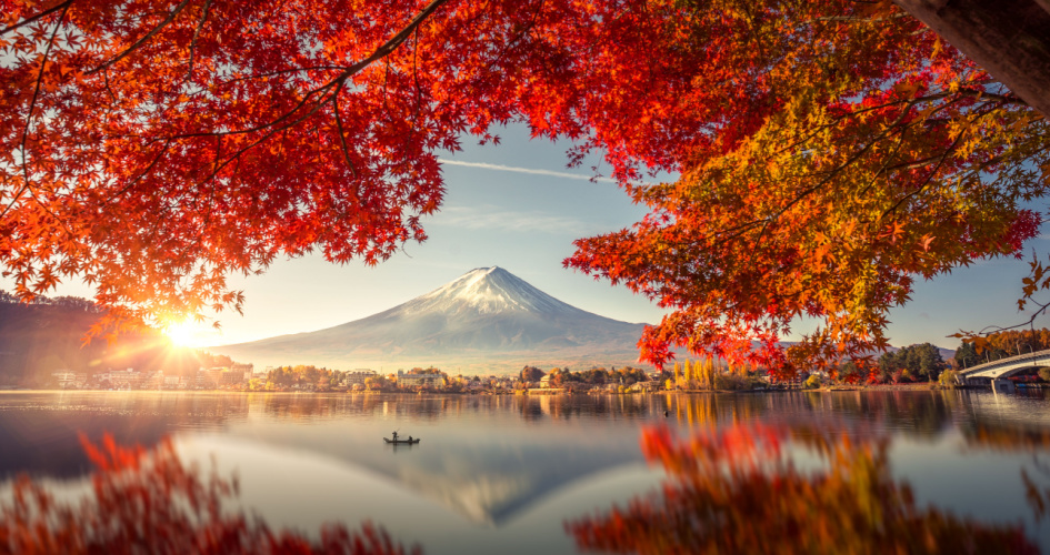 Mount Fuji towering over a village and a lake, behind red leaves. Concept of Japanese translation to English and professional Japanese translators.