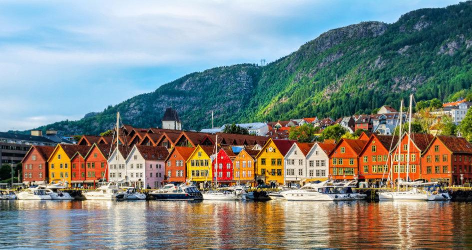 Bergen Harbour, a row of colourful wooden houses and boats in front. Concept of Norwegian translation services by professional Norwegian translators.