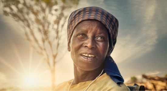 Old African woman with head scarf at sunset. 