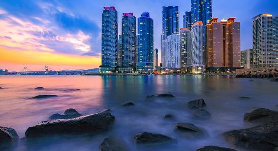 A city skyline as seen across the water at sunset.