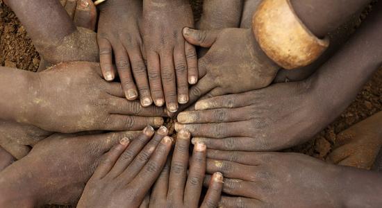 Close up of hands of African children put together on a soil ground. 