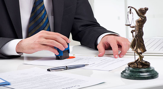 A man stamping paperwork at a desk with a Lady Justice statue. Concept of legal Arabic translation.