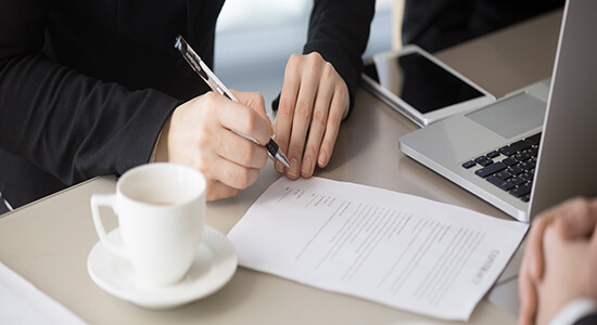 A man holding pen and signing on an official document. Concept of legal Latvian translation. 