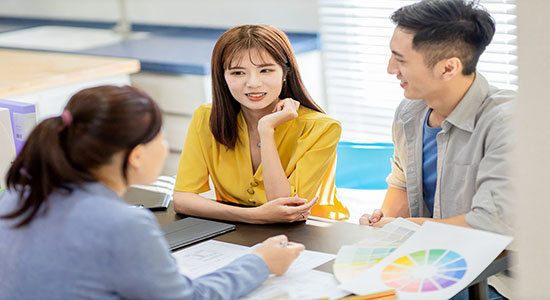 Two women and one man discussing work on table. 