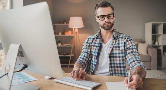 Smart Danish man working on computer and taking notes.