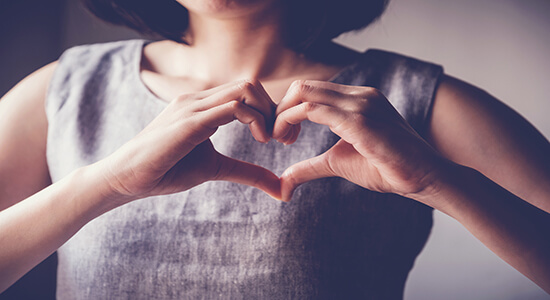 A woman making heart shape with hands. 