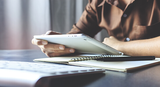 Man working on tablet with papers on table. 
