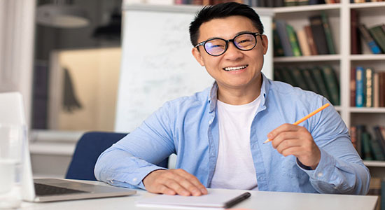 Asian man holding a pen and working on office's desk.