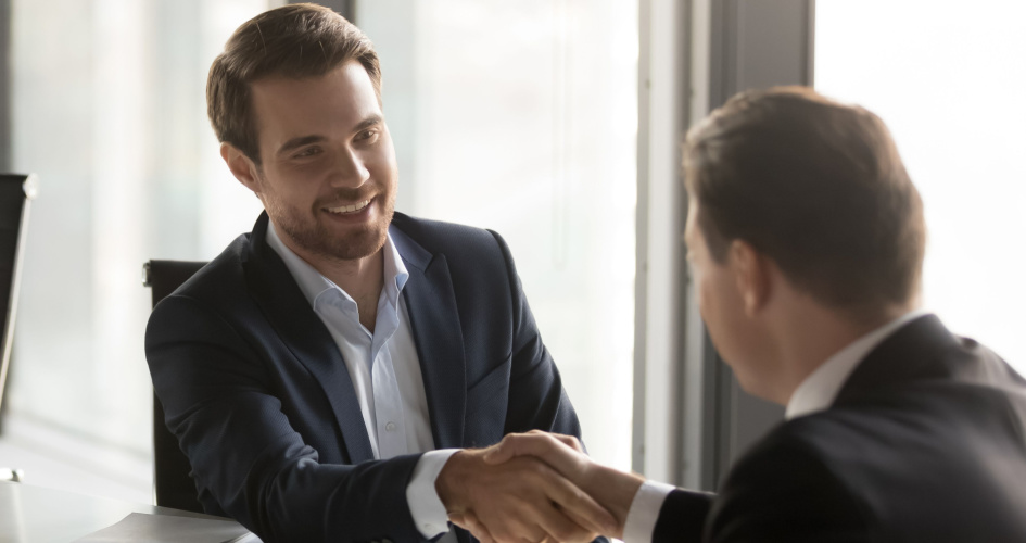 Man in business suit smiling and shaking hands with another person. Concept of business translation by professional business translators.