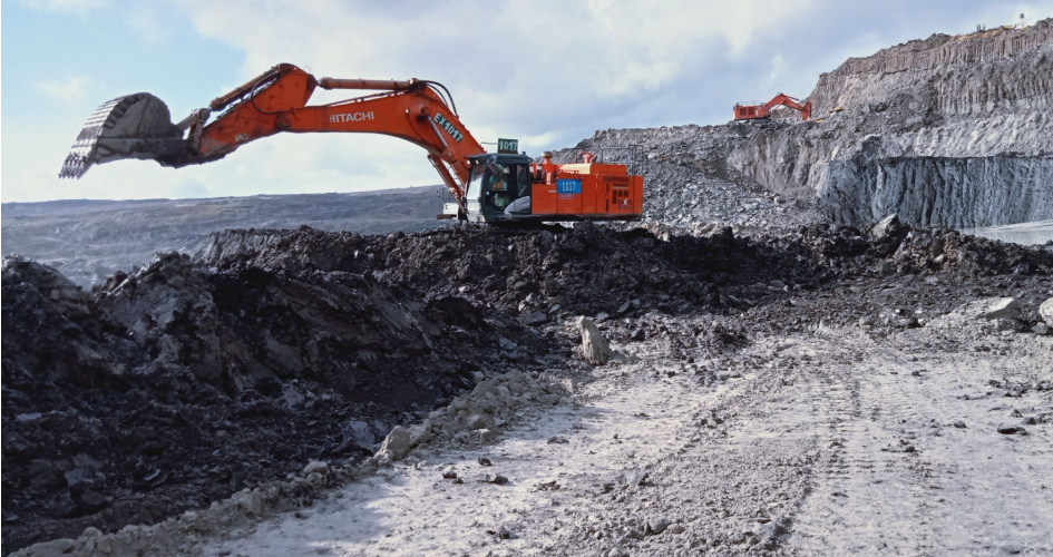 Two orange Hitachi excavators at a digging site. Concept of energy and mining translation.