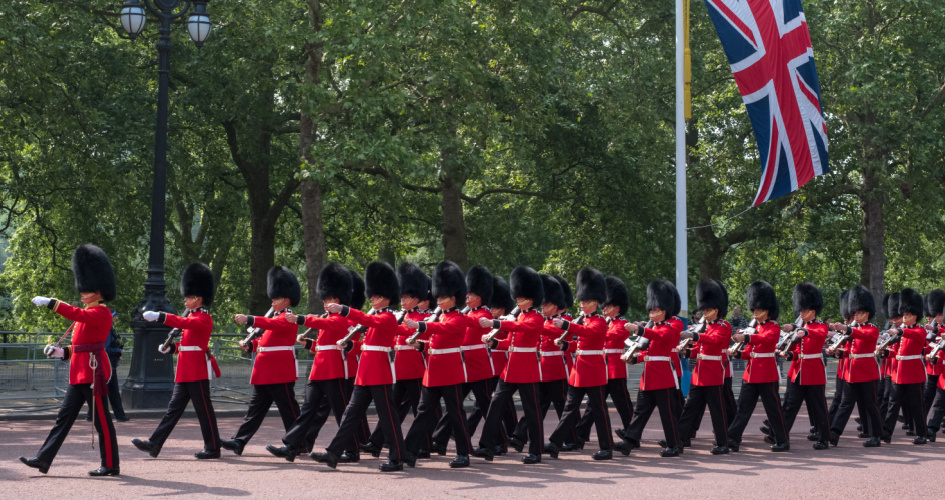 The King's Guard marching in their red and black uniforms. Concept of defence translation.
