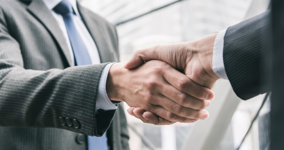 A close-up of two men in business clothes shaking hands. Concept of merger and acquisition translation.