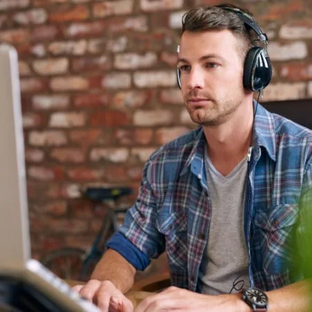 Handsome young man listening to audio while working in office. Concept of audio transcription.