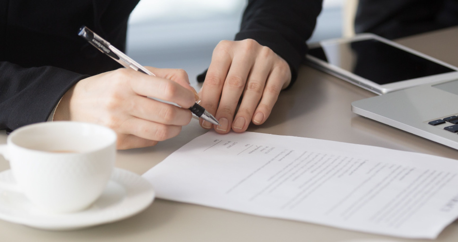 Close-up of a man's hand holding a pen about to sign contract. Concept of patent translation services.