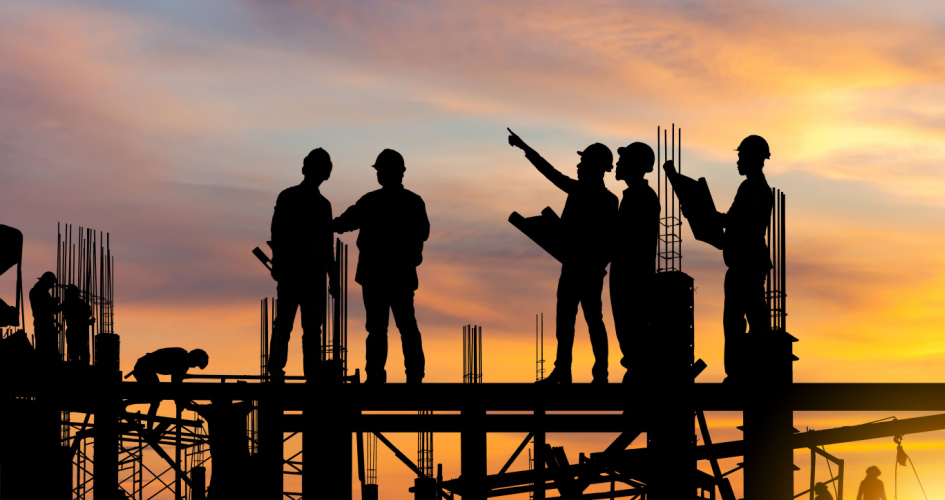 The silhouettes of five engineers discussing on a construction site at sunset. Concept of civil engineering technical translation services.