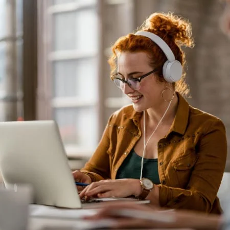 Professional woman using headphones listing to video while working at office. 
