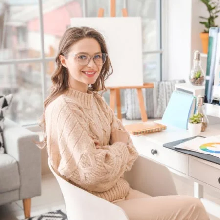 Smart graphic designers sitting on her desk in office with folded hands.