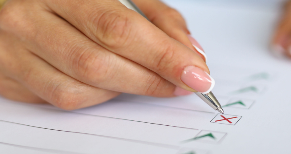 A woman's hand filling in a cross on a piece of paper. Concept of proofreading services and professional proofreaders.