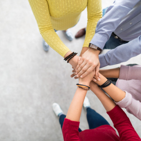 Young professional team putting their hands together showing solid teamwork. 