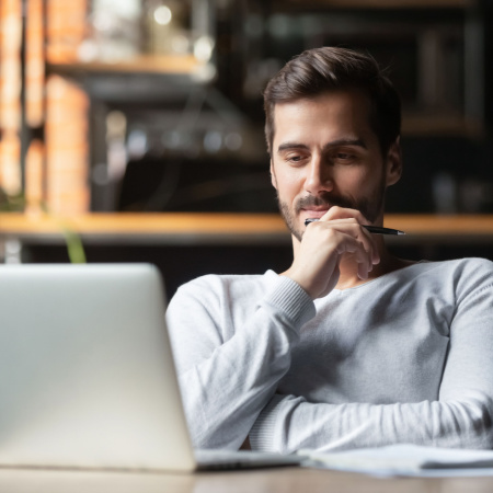 A man smiling while looking at a laptop.