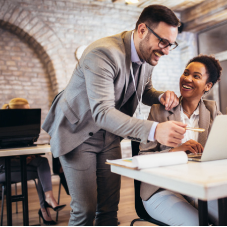 Professional man and woman working happily on a laptop in the office.