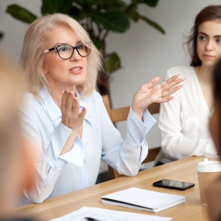 Mature professional woman explains her ideas in an office meeting.