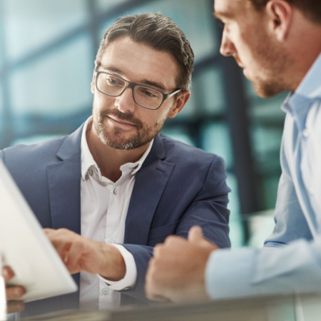 Two men working and discussing papers in office. 