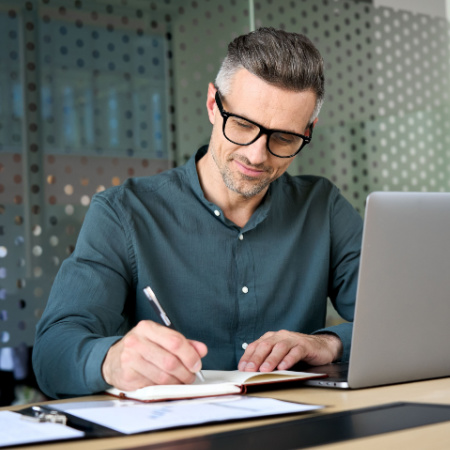 Professional man working on laptop in an office and taking notes. Concept of professional localisation.